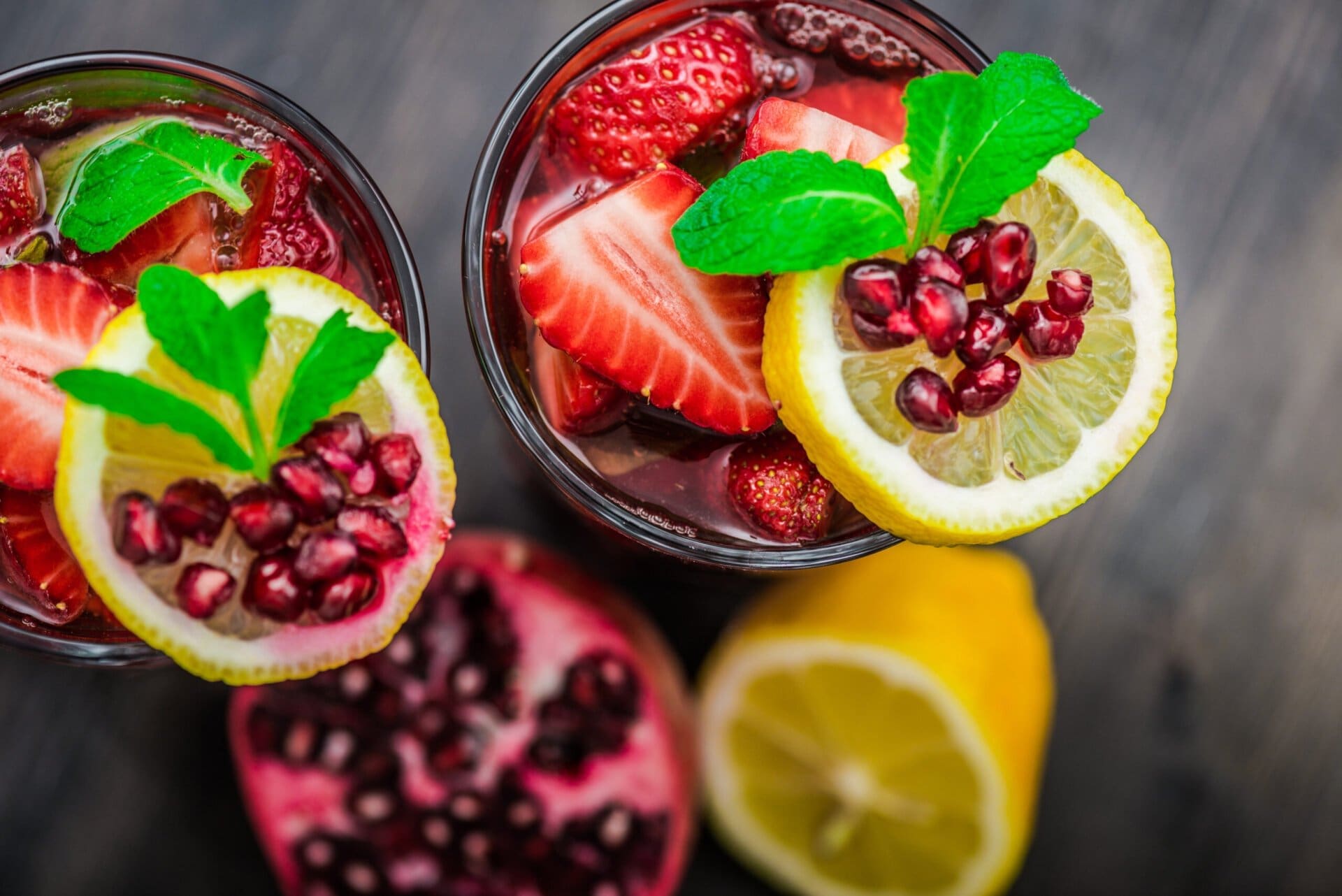 Two cups of Strawberry Cocktail and some fruits in the background